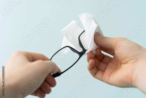 person's hands holding eye glasses and wipe the lenses, clean view sight