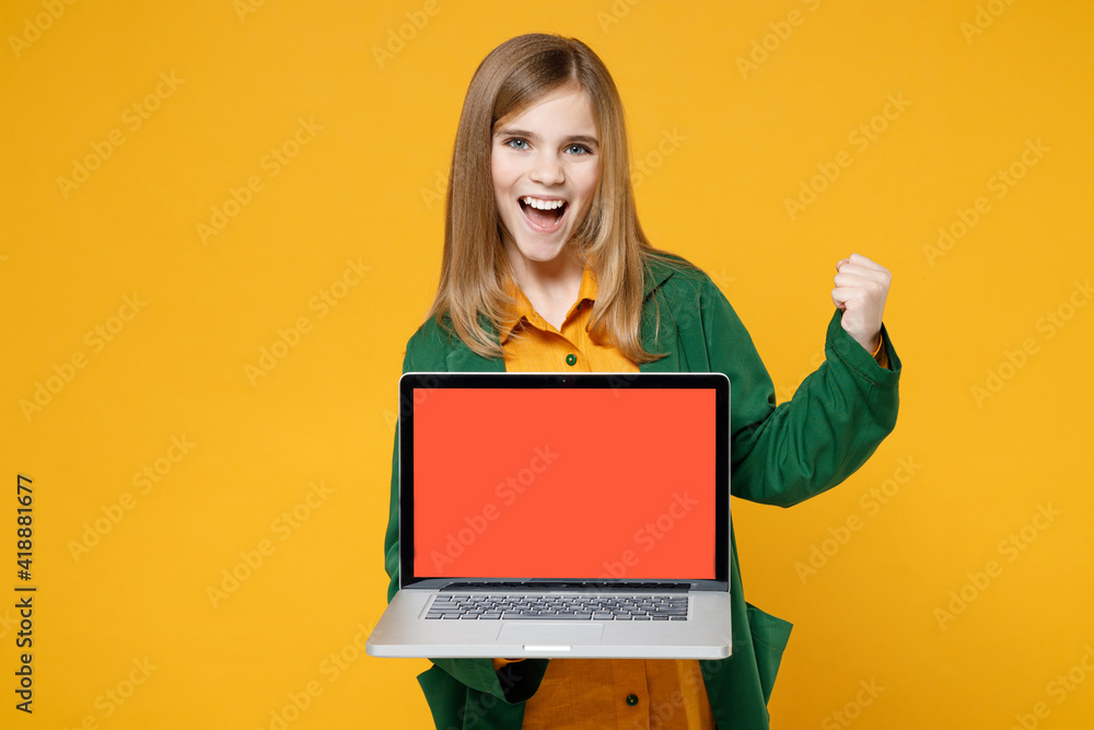 Little blonde kid girl 12-13 years old in casual clothes hold laptop pc computer blank screen workspace area do winner gesture isolated on yellow background children. Childhood lifestyle concept Little blonde kid girl 12-13 years old in casual clothes hold laptop pc computer blank screen workspace area do winner gesture isolated on yellow background children. Childhood lifestyle concept
