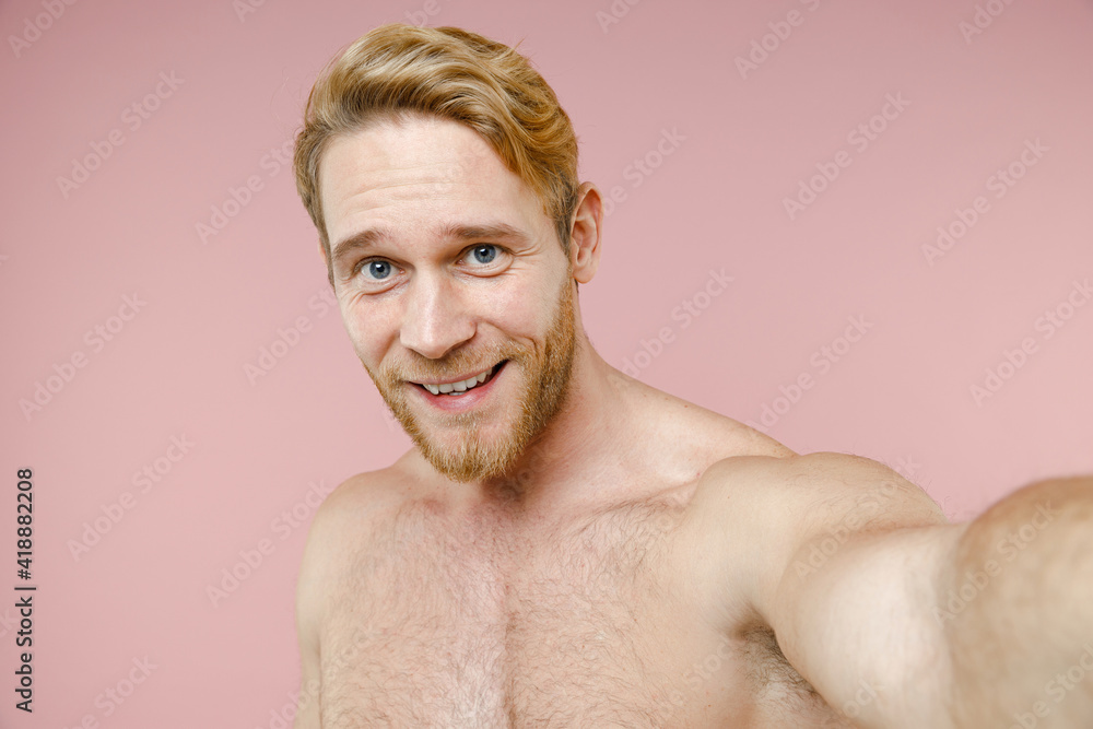 Fototapeta premium Close up of smiling bearded naked young man 20s years old perfect skin doing selfie shot on mobile phone isolated on pink background studio portrait. Skin care healthcare cosmetic procedures concept.