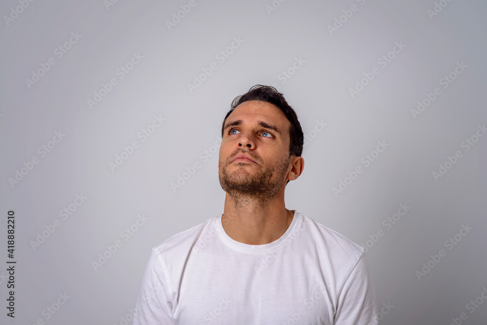 Portrait of a thoughtful man in a white T-shirt looking in the upper right corner Portrait of a thoughtful man in a white T-shirt looking in the upper right corner