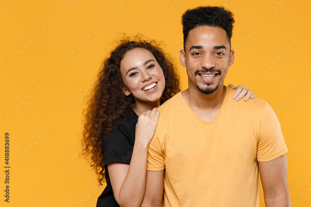 Obraz premium Young happy couple friends together family african smiling lovely woman man 20s wear black yellow t-shirt girlfiend hug boyfriend isolated on orange background studio portrait. Relationship concept.