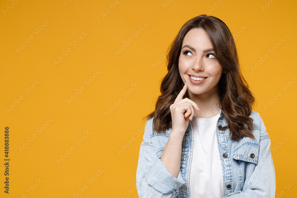 Young caucasian smiling dreamful wistful brunette woman in stylish casual denim shirt white t-shirt show prop up chin look aside isolated on yellow background studio portrait People lifestyle concept. Young caucasian smiling dreamful wistful brunette woman in stylish casual denim shirt white t-shirt show prop up chin look aside isolated on yellow background studio portrait People lifestyle concept.