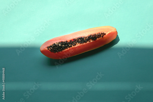 Slice of papaya on blue background with shadow.