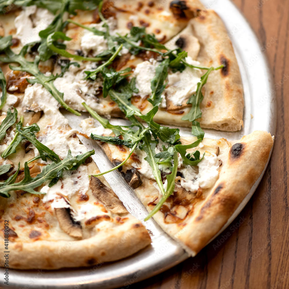 Tasty Pizza with mushrooms and arugula on wooden background. Traditional italian food, top view. Nutrition dinner or lunch.