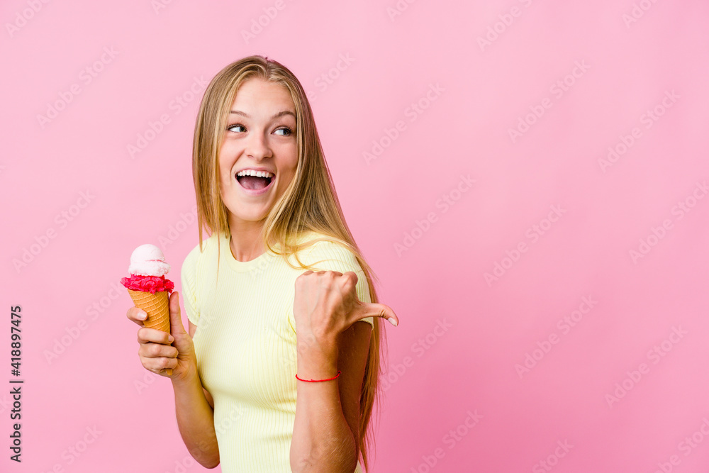 Young russian woman eating an ice cream isolated points with thumb finger away, laughing and carefree. Young russian woman eating an ice cream isolated points with thumb finger away, laughing and carefree.