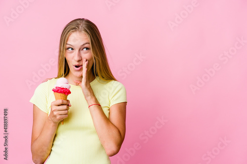 Young russian woman eating an ice cream isolated is saying a secret hot braking news and looking aside