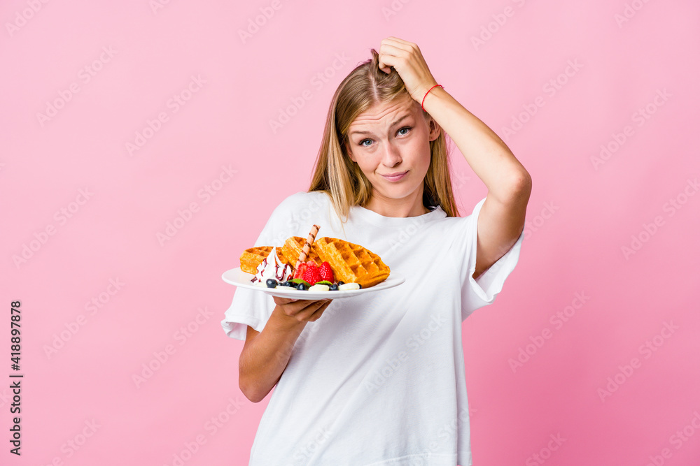 Young russian woman eating a waffle isolated being shocked, she has remembered important meeting.