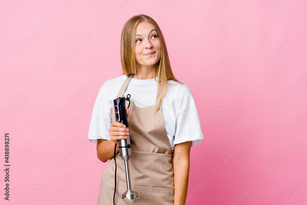Young russian cook woman holding an electric mixer isolated dreaming of achieving goals and purposes