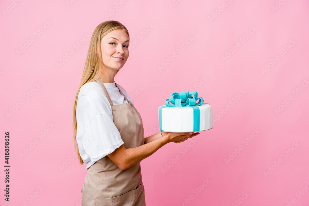 Young russian baker woman holding a delicious cake holding a copy space on a palm. Young russian baker woman holding a delicious cake holding a copy space on a palm.