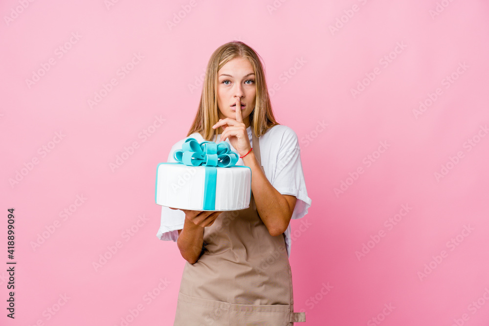 Young russian baker woman holding a delicious cake keeping a secret or asking for silence. Young russian baker woman holding a delicious cake keeping a secret or asking for silence.