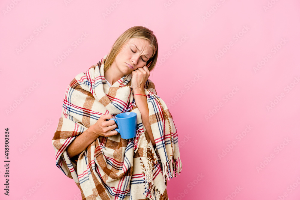 Young russian woman wrapped in a blanket drinking coffee who feels sad and pensive, looking at copy space. Young russian woman wrapped in a blanket drinking coffee who feels sad and pensive, looking at copy space.