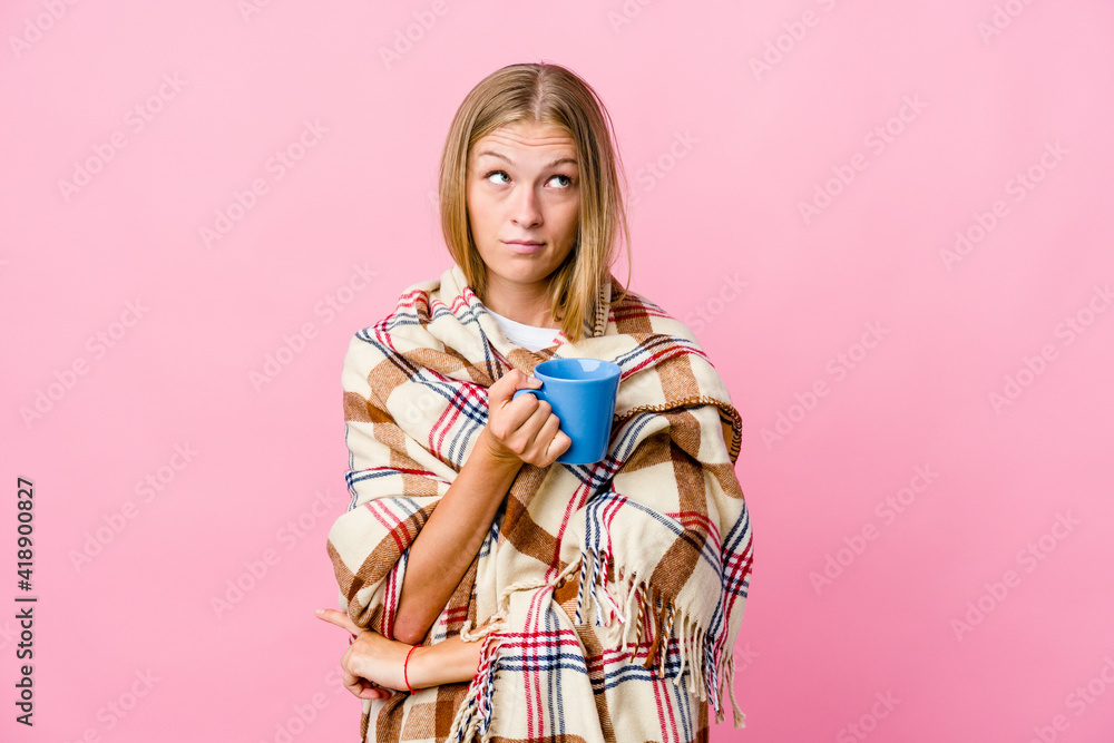 Young russian woman wrapped in a blanket drinking coffee tired of a repetitive task. Young russian woman wrapped in a blanket drinking coffee tired of a repetitive task.