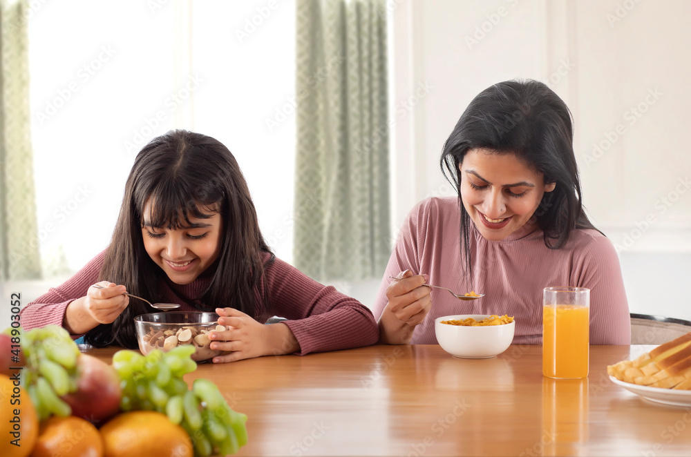 A HAPPY MOTHER AND DAUGHTER EATING BREAKFAST TOGETHER A HAPPY MOTHER AND DAUGHTER EATING BREAKFAST TOGETHER