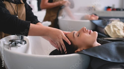 Beauty salon barber woman massage head of customer during wash hair of beautiful woman and she look relax and happy. Beauty business for healthy and good appearance of people concept.