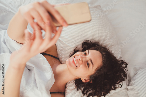 Beautiful woman using mobile phone to selfie while laying on bed