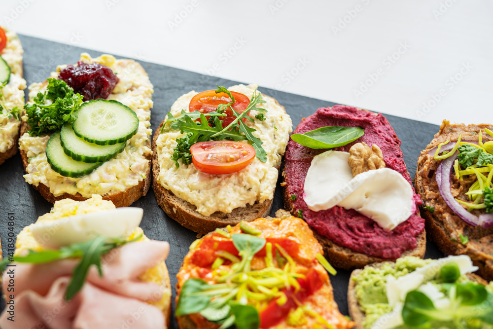 selection board of open sandwiches dips, spreads, cold cut meat, cheese, egg and salad 