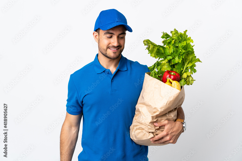 Delivery man with vegetables isolated on white background with happy expression Delivery man with vegetables isolated on white background with happy expression