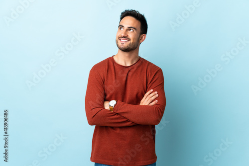 Young handsome man over isolated background looking up while smiling