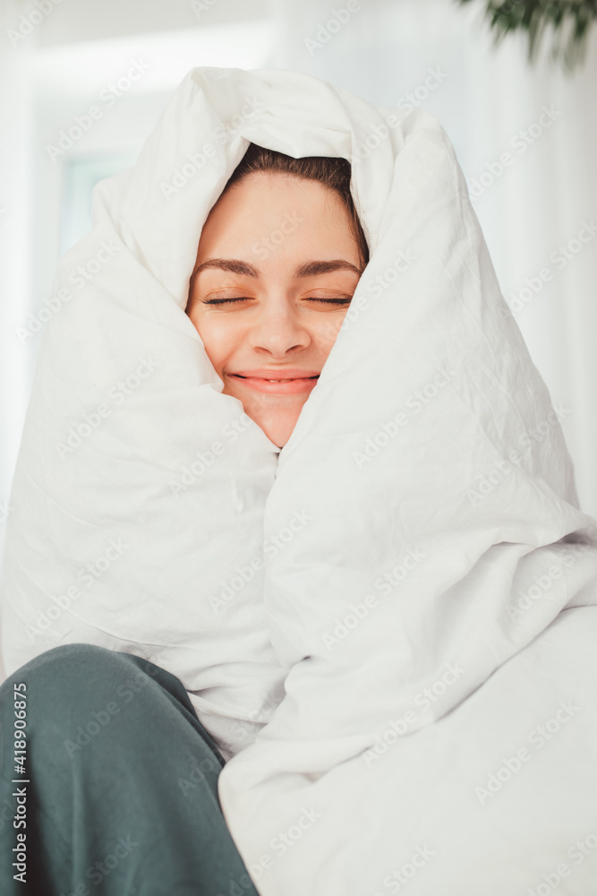 Portrait view of a smiling young curly female wrapped in a soft white blanket Portrait view of a smiling young curly female wrapped in a soft white blanket