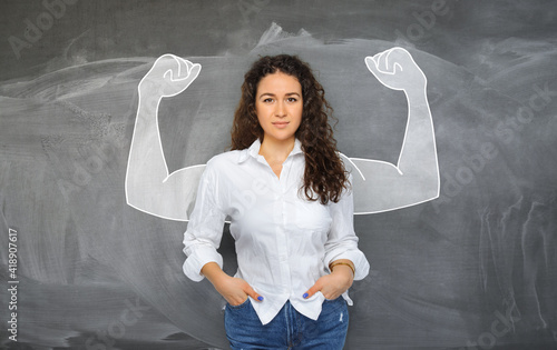 portrait of young self-confident woman looks in camera and shows muscle