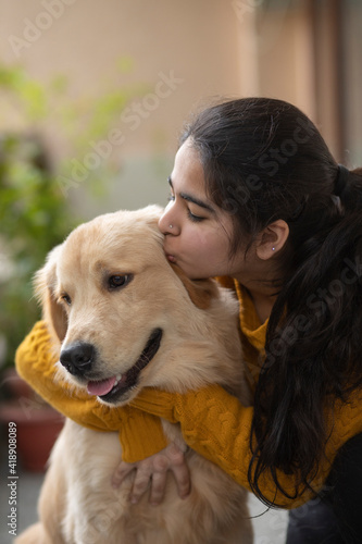 A YOUNG GIRL HAPPILY KISSING PET DOG 