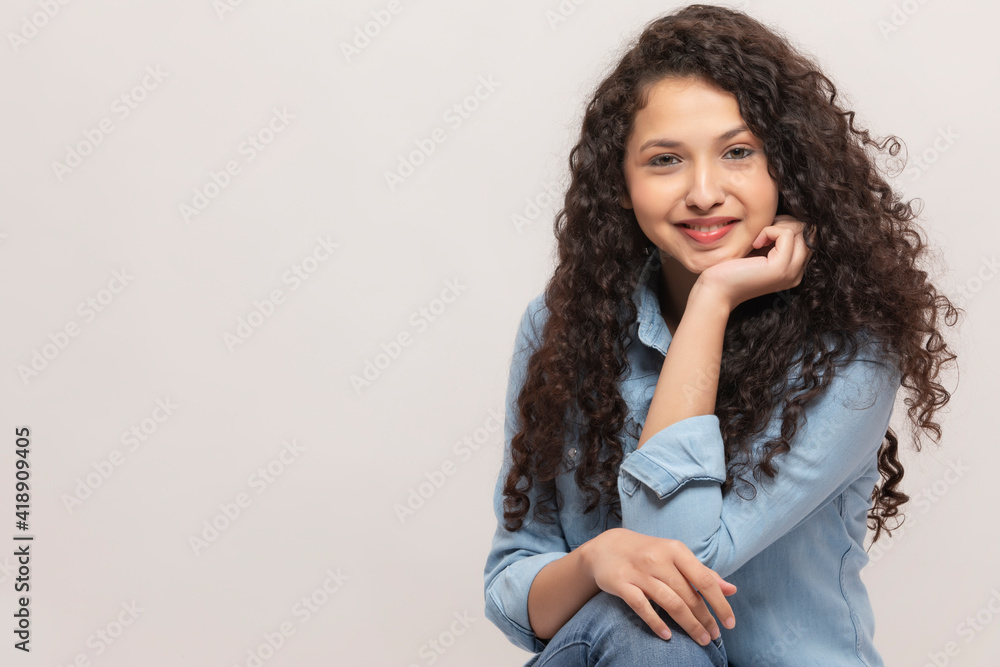 PORTRAIT OF A CURLY HAIRED TEENAGE GIRL LOOKING AT CAMERA AND SMILING PORTRAIT OF A CURLY HAIRED TEENAGE GIRL LOOKING AT CAMERA AND SMILING