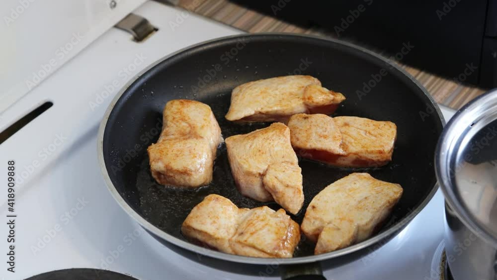 Closeup view of pieces of chicken meat are fried and mixed in a pan. Shallow focus. Closeup view of pieces of chicken meat are fried and mixed in a pan. Shallow focus.