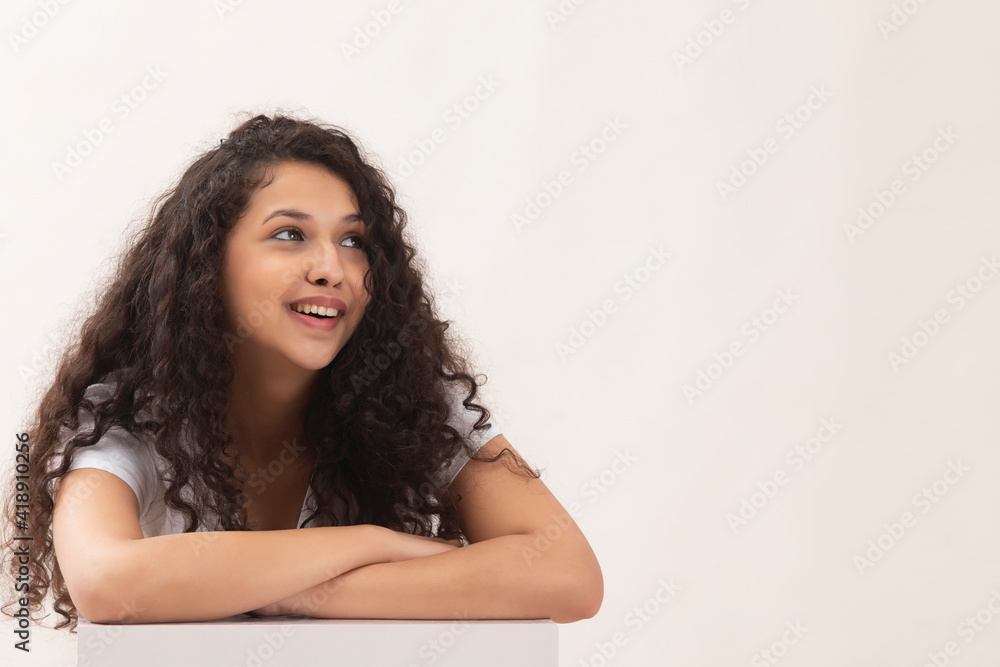 A HAPPY TEENAGER WITH CURLY HAIR SITTING AND LOOKING AWAY A HAPPY TEENAGER WITH CURLY HAIR SITTING AND LOOKING AWAY