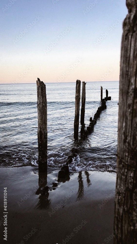 Holzpfäle am Stand im Meer