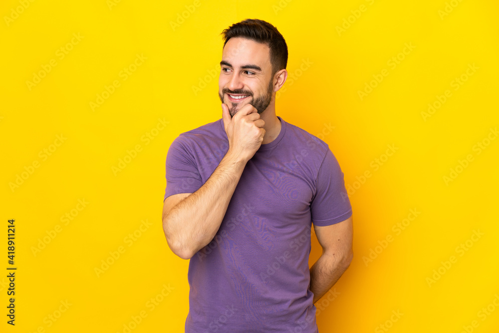 Young caucasian handsome man isolated on yellow background looking to the side and smiling Young caucasian handsome man isolated on yellow background looking to the side and smiling