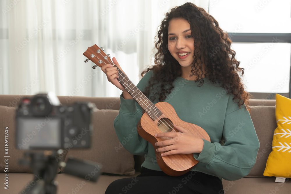Fototapeta premium A TEENAGER PLAYING UKULELE AND RECORDING THE PERFORMANCE 