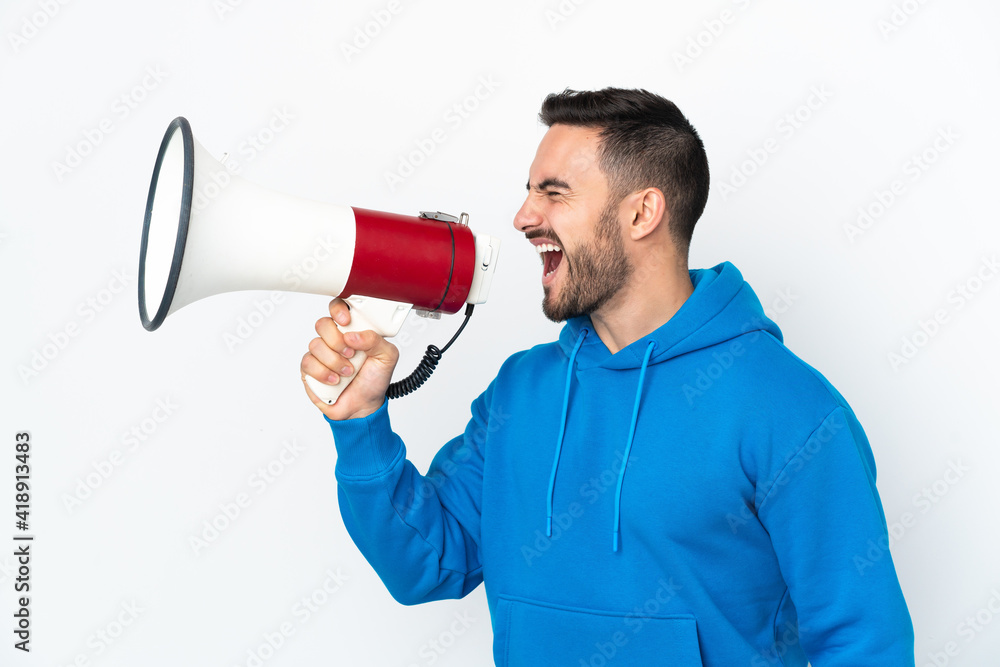 Young caucasian handsome man isolated on white background shouting through a megaphone to announce something in lateral position Young caucasian handsome man isolated on white background shouting through a megaphone to announce something in lateral position
