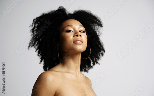 Black healthy curly hair. Clean, even skin of the face. portrait of a female model of Latin American appearance. Photo shoot in a photo studio on a white background.