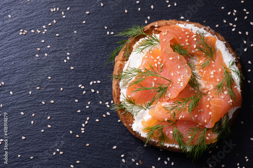 appetizing half of a bun with smoked fish, fresh cream, sprinkled with dill and sesame seeds