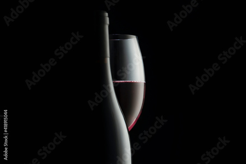 Elegant red wine glass and a wine bottles in black background © Vladimir Razgulyaev