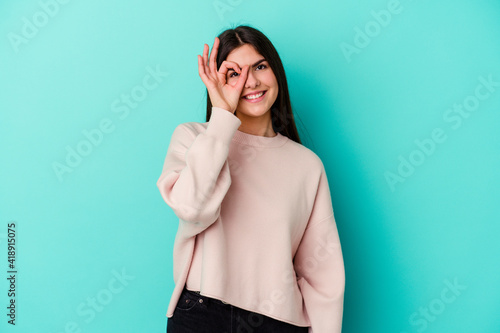Young caucasian woman isolated on blue background excited keeping ok gesture on eye.