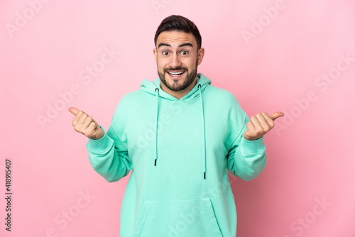 Young caucasian handsome man isolated on pink background with thumbs up gesture and smiling © luismolinero