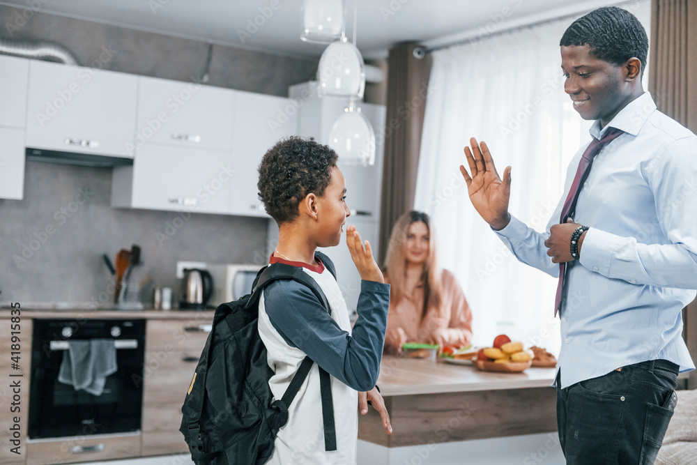 Multiracial family is together at home at daytime. Father prepares boy for a walk Multiracial family is together at home at daytime. Father prepares boy for a walk