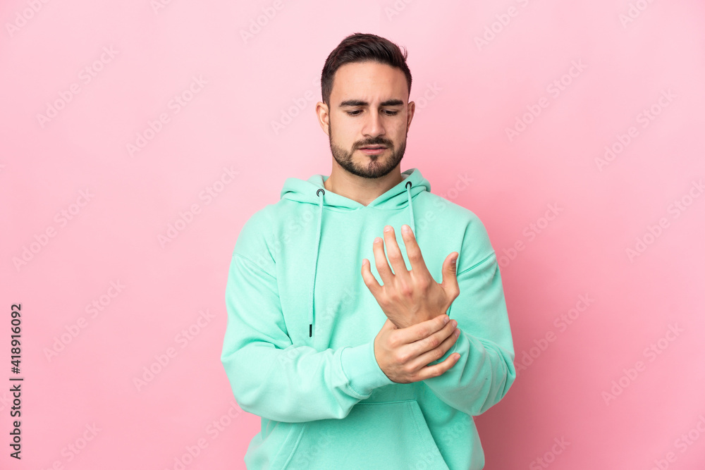 Young caucasian handsome man isolated on pink background suffering from pain in hands Young caucasian handsome man isolated on pink background suffering from pain in hands