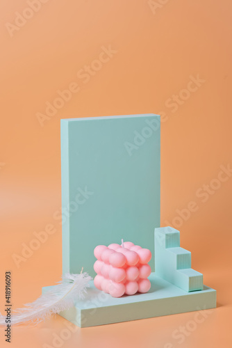 A trendy pink soy cube bubble candle on a blue podium