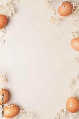 Easter eggs with flowers on pastel beige background. Flat lay, copy space.