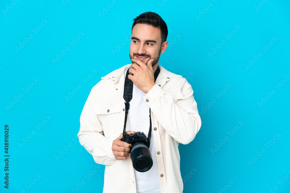 Young photographer man isolated on blue background looking to the side and smiling Young photographer man isolated on blue background looking to the side and smiling
