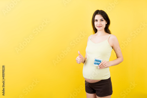 heap of blisters of pills in pregnant woman s hand at colorful background with copy space. Healthcare and treatment during pregnancy concept