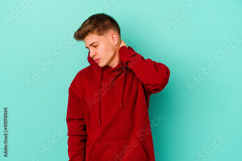 Young caucasian man isolated on blue background having a neck pain due to stress, massaging and touching it with hand.