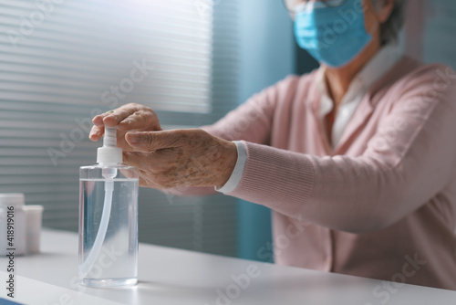 Senior woman applying sanitizer on her hands