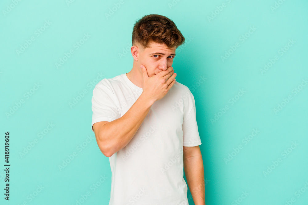 Young caucasian man isolated on blue background covering mouth with hands looking worried. Young caucasian man isolated on blue background covering mouth with hands looking worried.