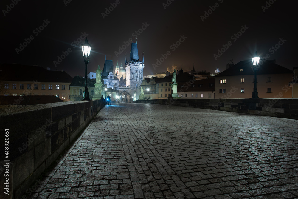 Fototapeta premium empty sidewalk on the illuminated Charles Bridge at night in the center of Prague