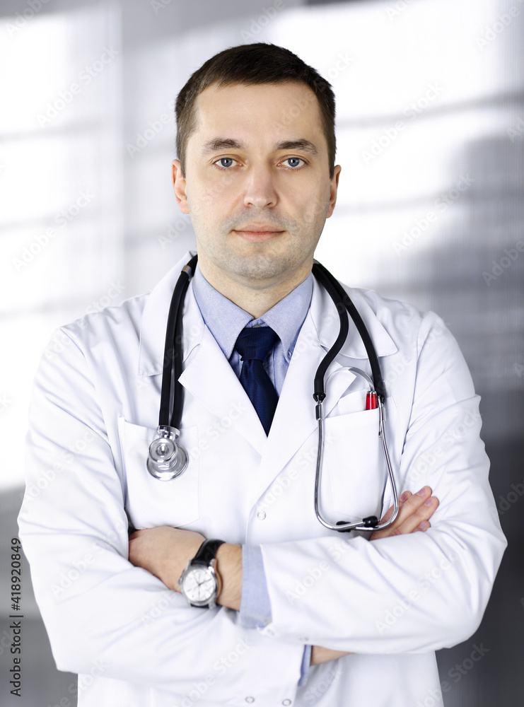 Professional doctor with a stethoscope is standing with crossed arms in a clinic. Perfect medical service in hospital. Medicine and healthcare concept Professional doctor with a stethoscope is standing with crossed arms in a clinic. Perfect medical service in hospital. Medicine and healthcare concept