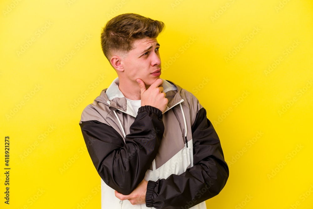 Fototapeta premium Young caucasian man isolated on yellow background thinking and looking up, being reflective, contemplating, having a fantasy.