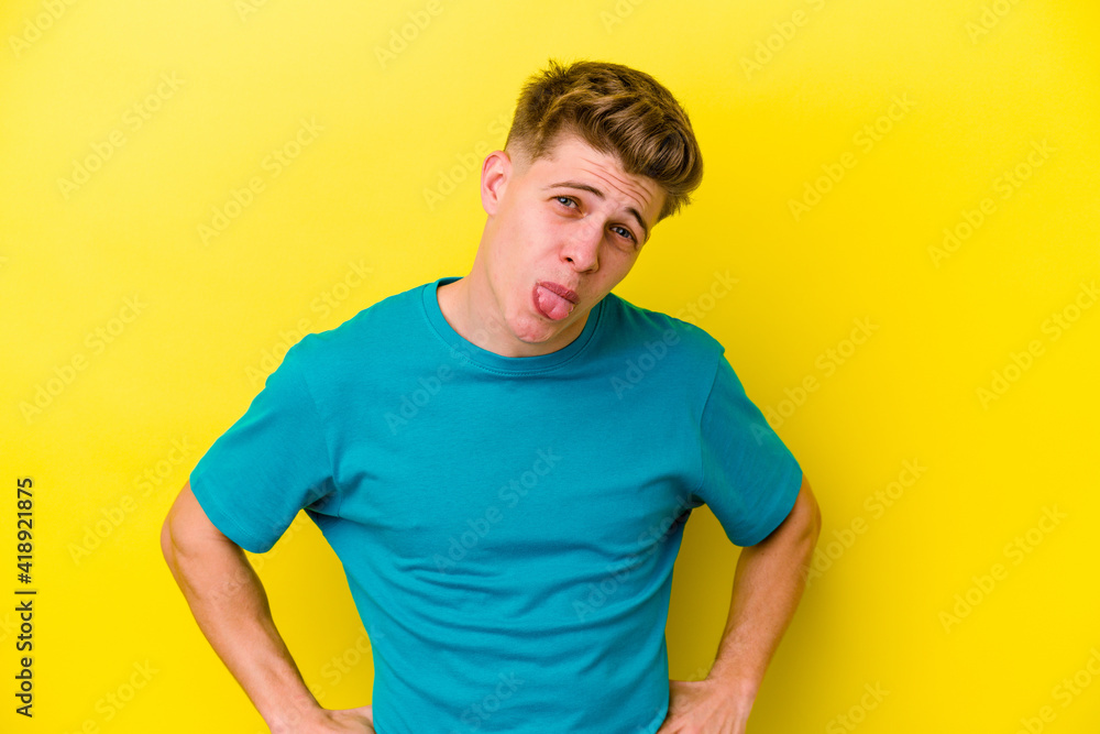 Young caucasian man isolated on yellow background funny and friendly sticking out tongue. Young caucasian man isolated on yellow background funny and friendly sticking out tongue.